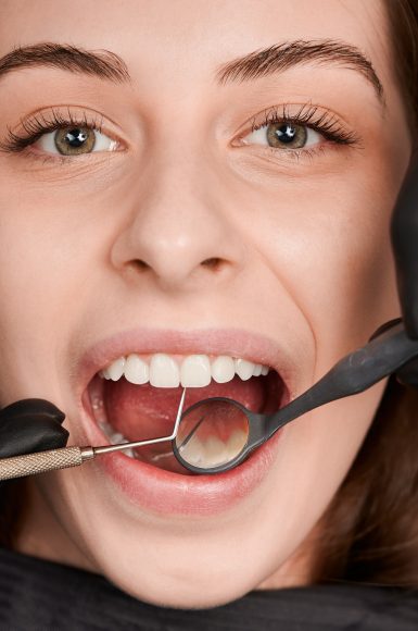 Dentist hands in sterile gloves examining woman teeth.